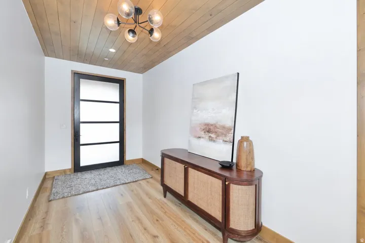 Wood-finish flooring, wood-paneled ceiling, recessed lighting, and a contemporary black chandelier with clear glass globes