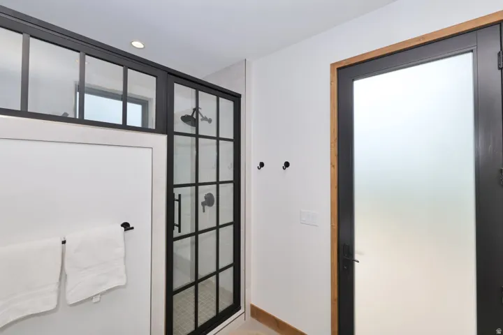 Walk-in shower with black grid-patterned glass enclosure and matte black fixtures