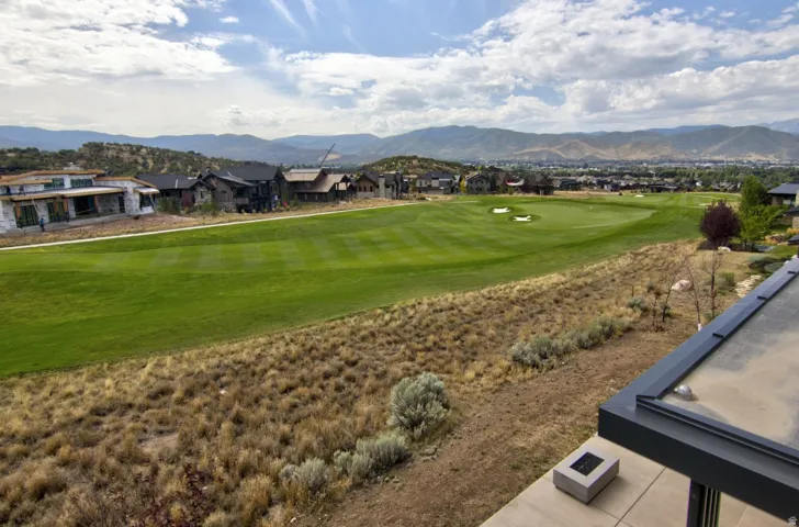 Expansive green golf course with sand traps and surrounding mountain range