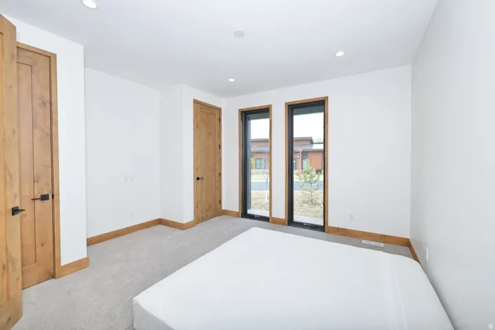 White walls with recessed lighting, wood-finish doors with black hardware, wood-finish trim, carpeting, and two large windows with black frames