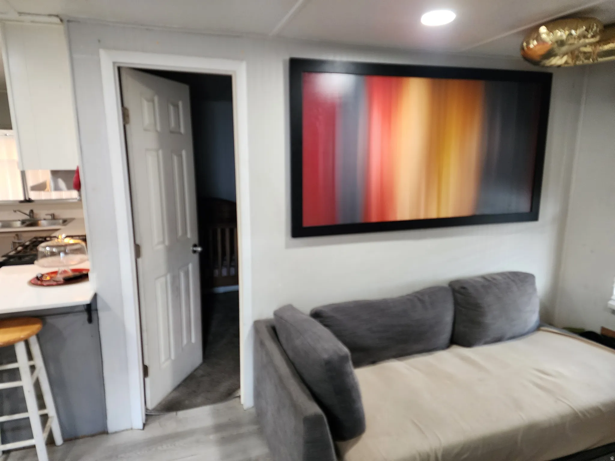 Recessed lighting illuminates this space, featuring wood-finish flooring and a kitchen area with a countertop