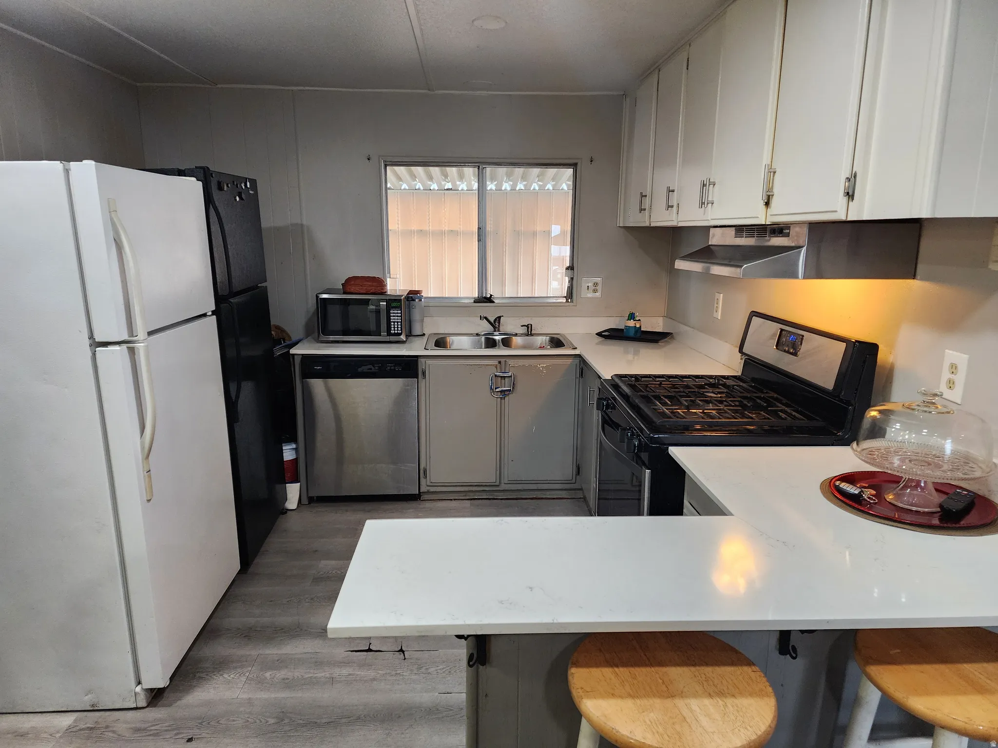 Kitchen featuring white cabinetry, light-toned countertops, a stainless steel gas range, and wood-finish flooring