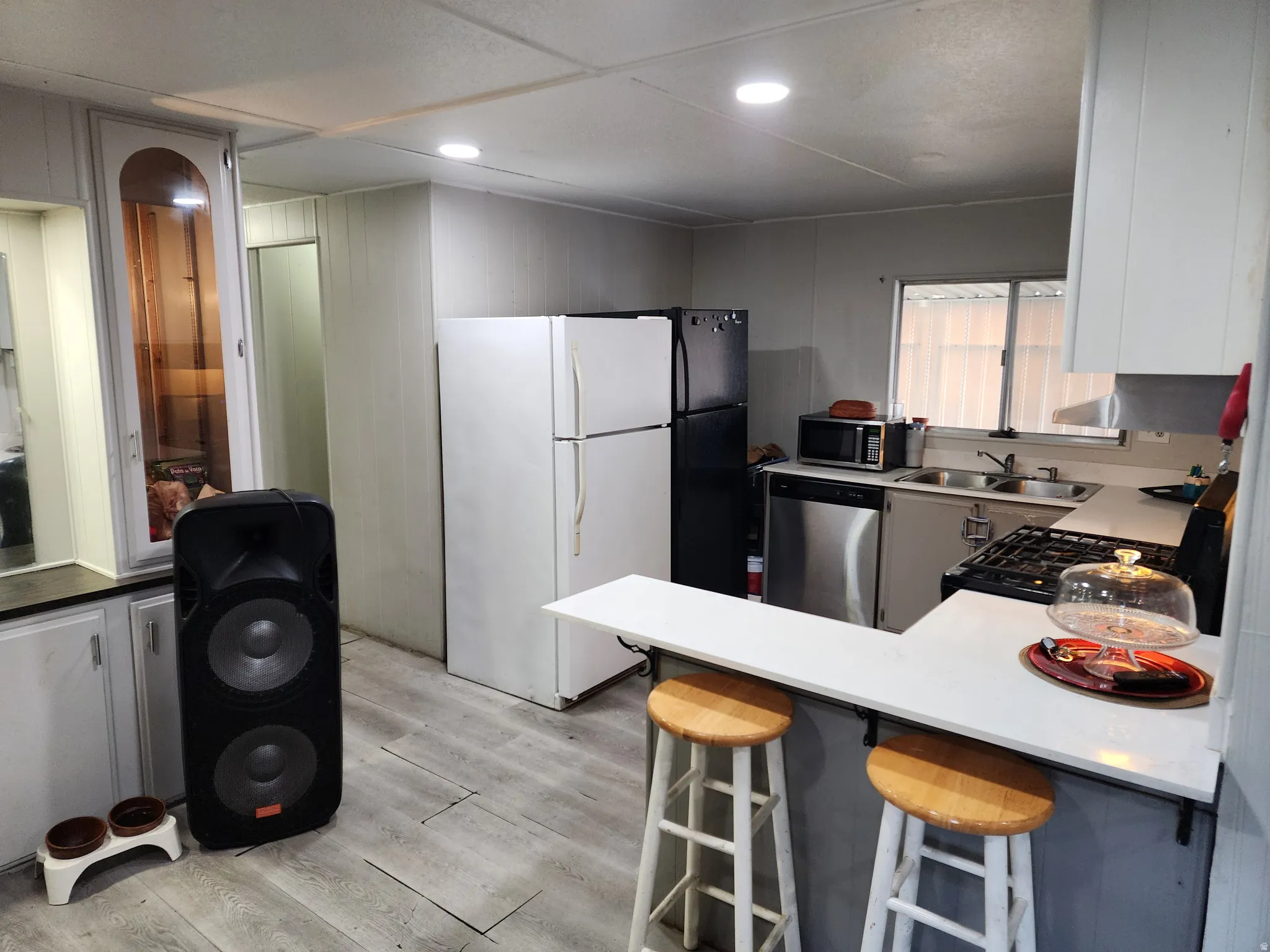 Kitchen featuring a breakfast bar, recessed lighting, wood-finish flooring, a stainless steel dishwasher, and a gas range