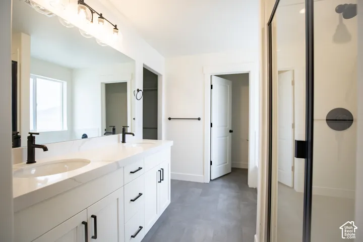 Primary bath with dual sinks, painted white wood cabinets, quartz slab countertops, soaker tub and walk-in shower.