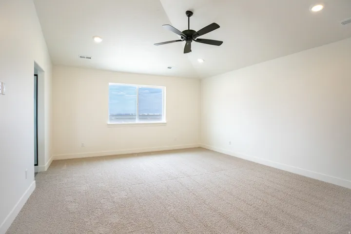Spacious primary bedroom with vaulted ceiling and ceiling fan.