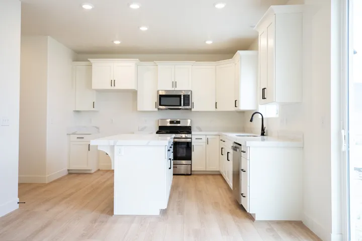 Terrific kitchen with 6' island, 42" uppers, painted white wood cabinets, quartz slab countertops, gas range, built-in dishwasher, microwave and disposal.