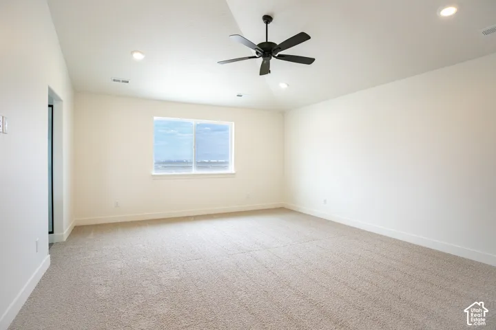 Spacious primary bedroom with vaulted ceiling and ceiling fan.