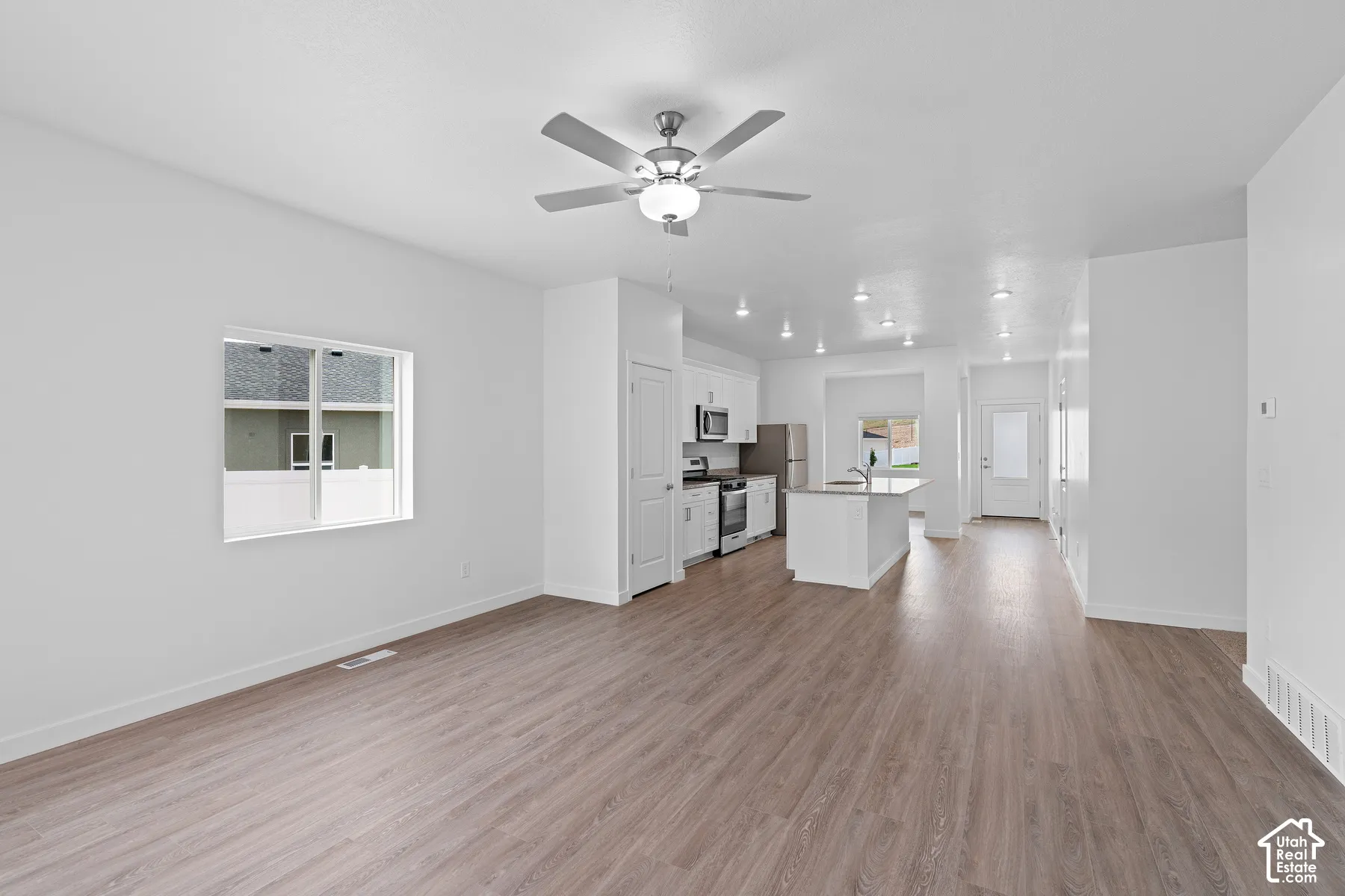 Open-concept living area featuring wood-finish flooring, recessed lighting, and a ceiling fan