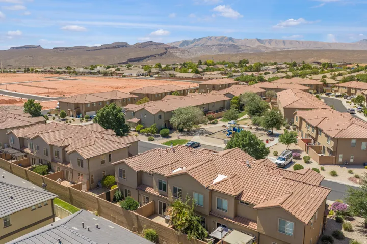 Residential community with tile roofs, stucco exteriors, and a central common area featuring a play structure and mature landscaping