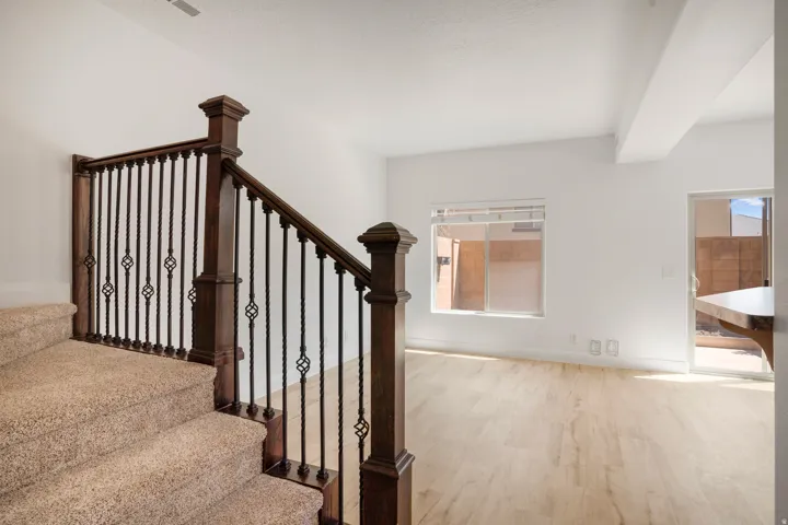 Carpeted staircase featuring wood newel posts and wrought iron balusters