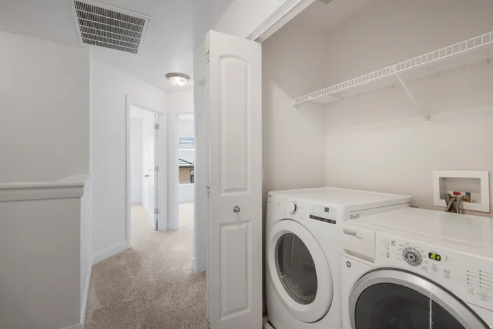 Laundry area featuring a stacked washer and dryer, with overhead wire shelving, and a bi-fold door