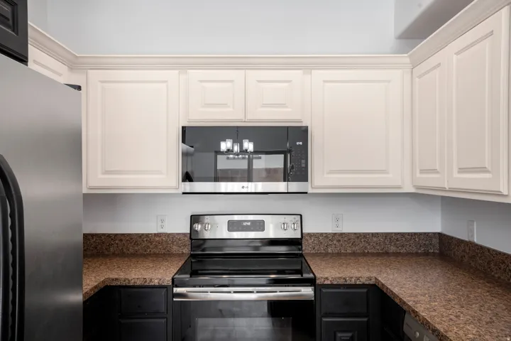 White upper cabinetry with crown molding, stainless steel appliances, and L-shaped countertop