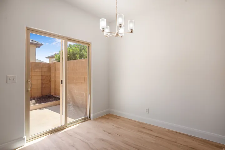 Sliding glass door, light wood-finish flooring, white walls, and a contemporary chandelier with four frosted glass shades