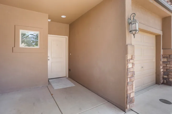 Stucco exterior with stone accents, recessed entryway, panel garage door, and decorative outdoor lighting fixture
