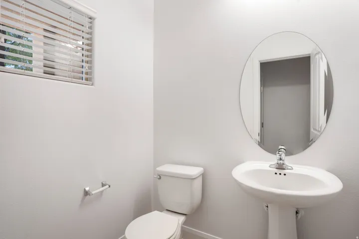 Oval mirror above a pedestal sink with a chrome faucet