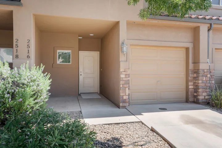Stucco exterior with stone accents, covered entry, attached garage, concrete driveway, and low-maintenance landscaping