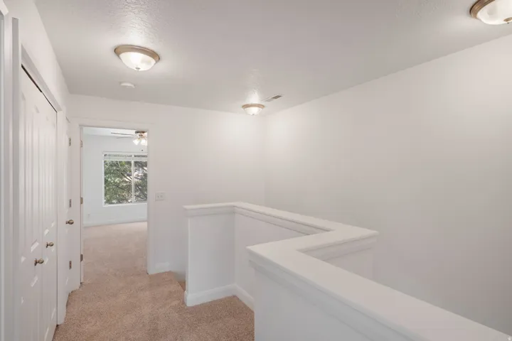 Carpeted hallway with built-in railing, white paneled doors, and flush-mount lighting fixtures