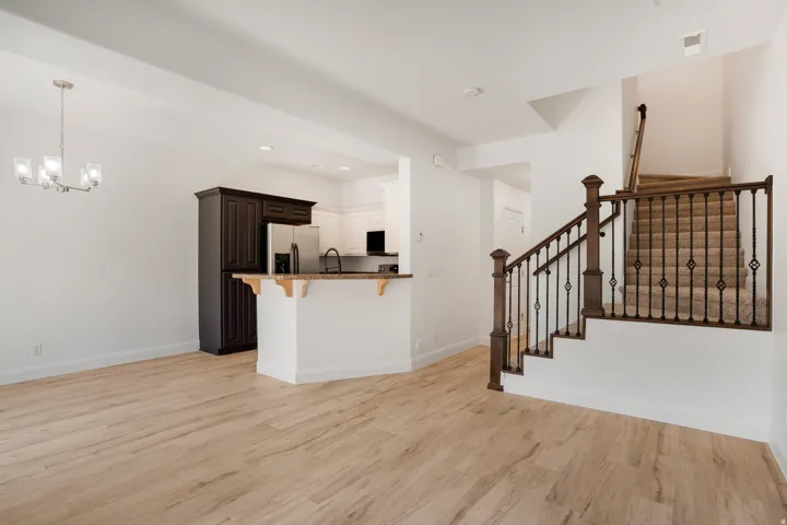 Open-concept living space featuring wood-finish flooring, a contemporary chandelier, and a kitchen island with a stone-finish countertop
