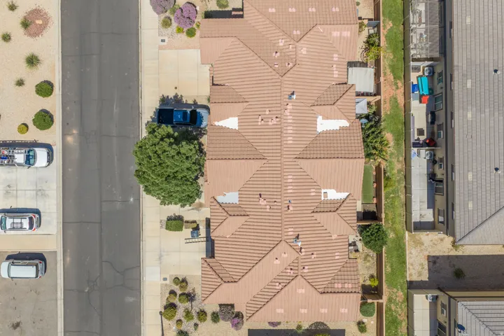 Tile roof architecture, concrete driveway, landscaped front yard, adjacent green space, and paved street