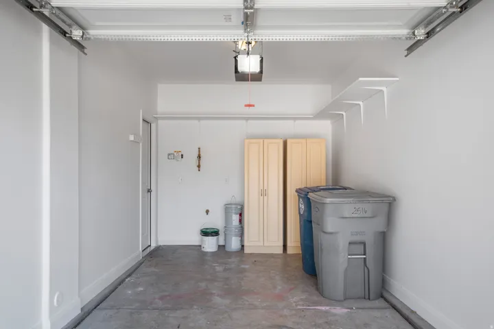 Attached garage featuring a concrete floor, built-in shelving, and wood-finish cabinetry