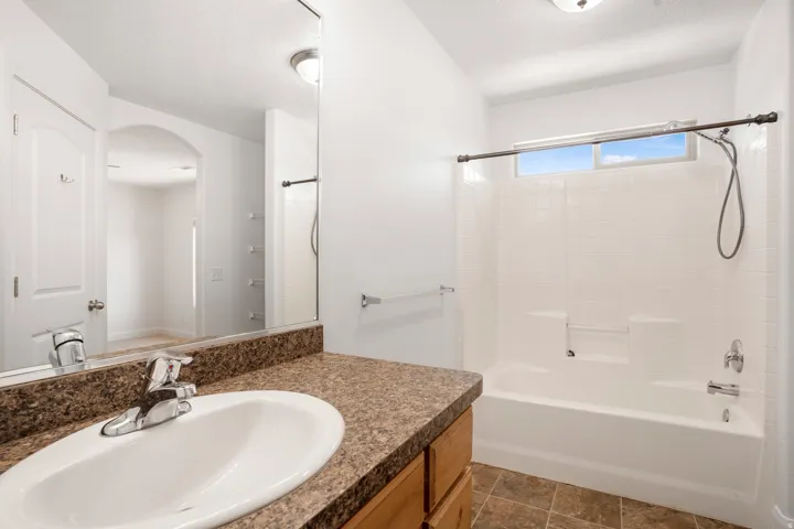 Bathroom featuring a bathtub with shower, vanity with an integrated sink, and tile flooring