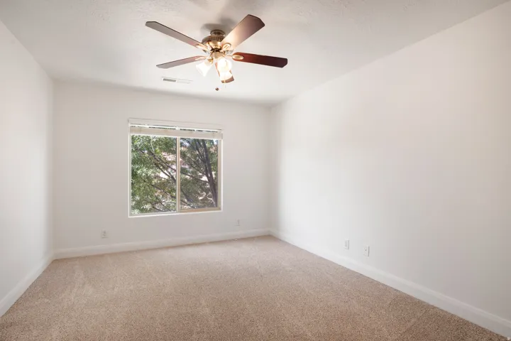Wall-to-wall carpeted flooring, white painted walls, and a ceiling fan with integrated lighting
