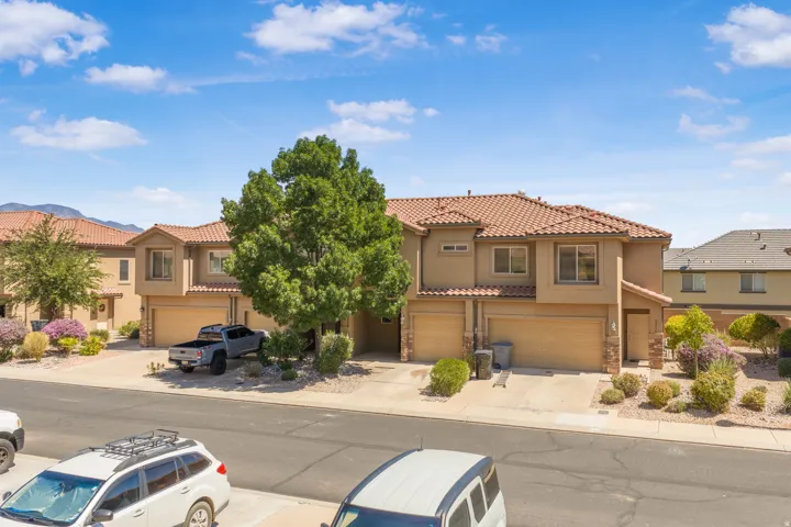 Two-story stucco exterior with a terra cotta tile roof, multiple attached garages, and a paved driveway