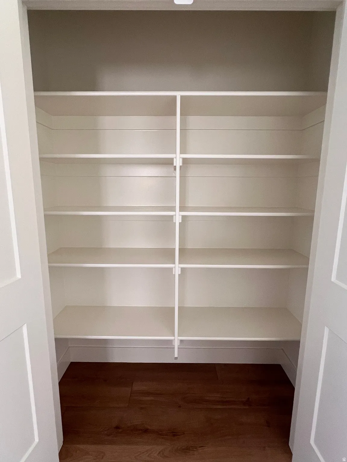 Built-in shelving, wood-finish flooring, and white bifold doors