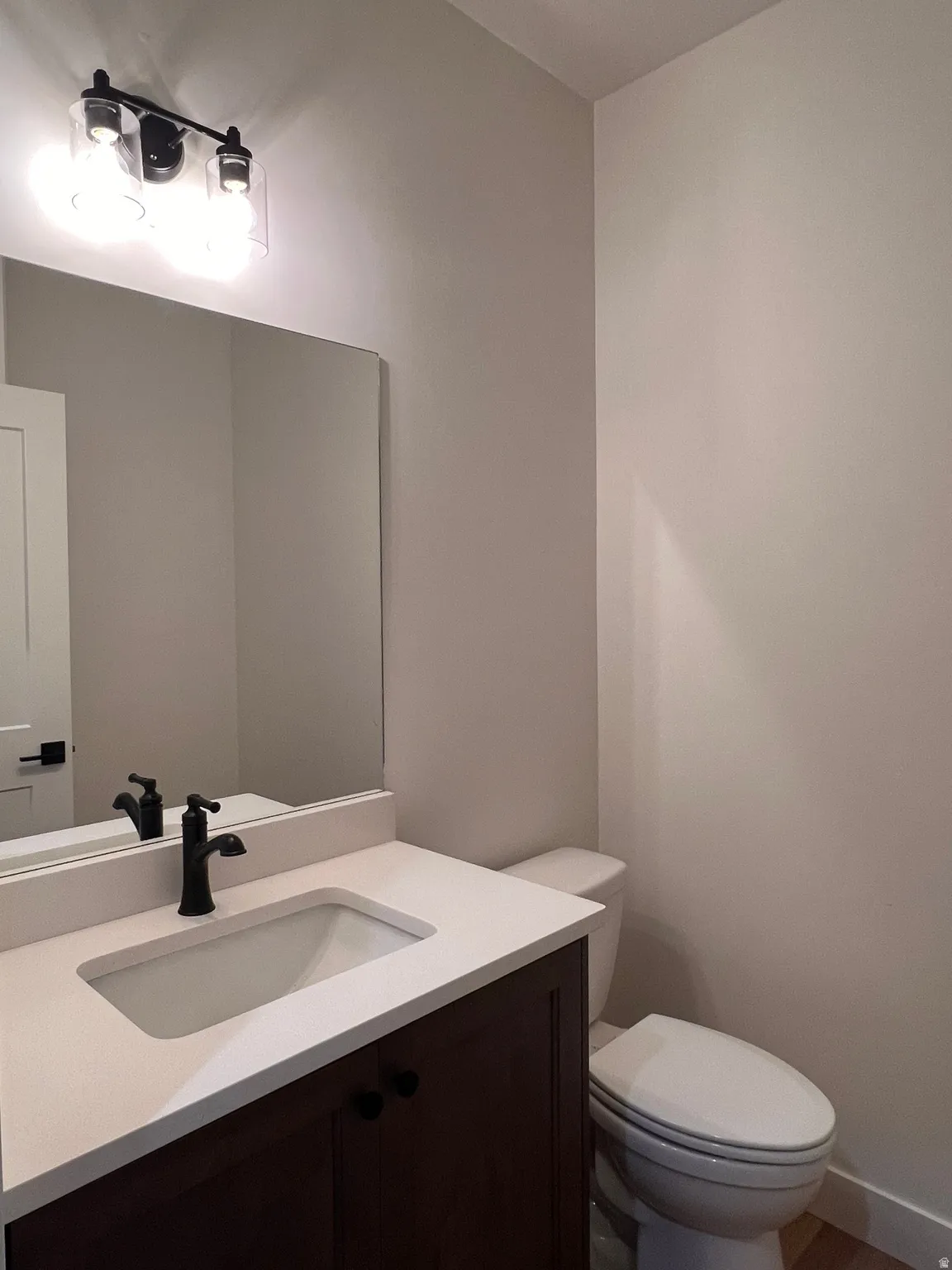 Modern vanity with dark wood-finish cabinetry, integrated rectangular sink, and light countertop