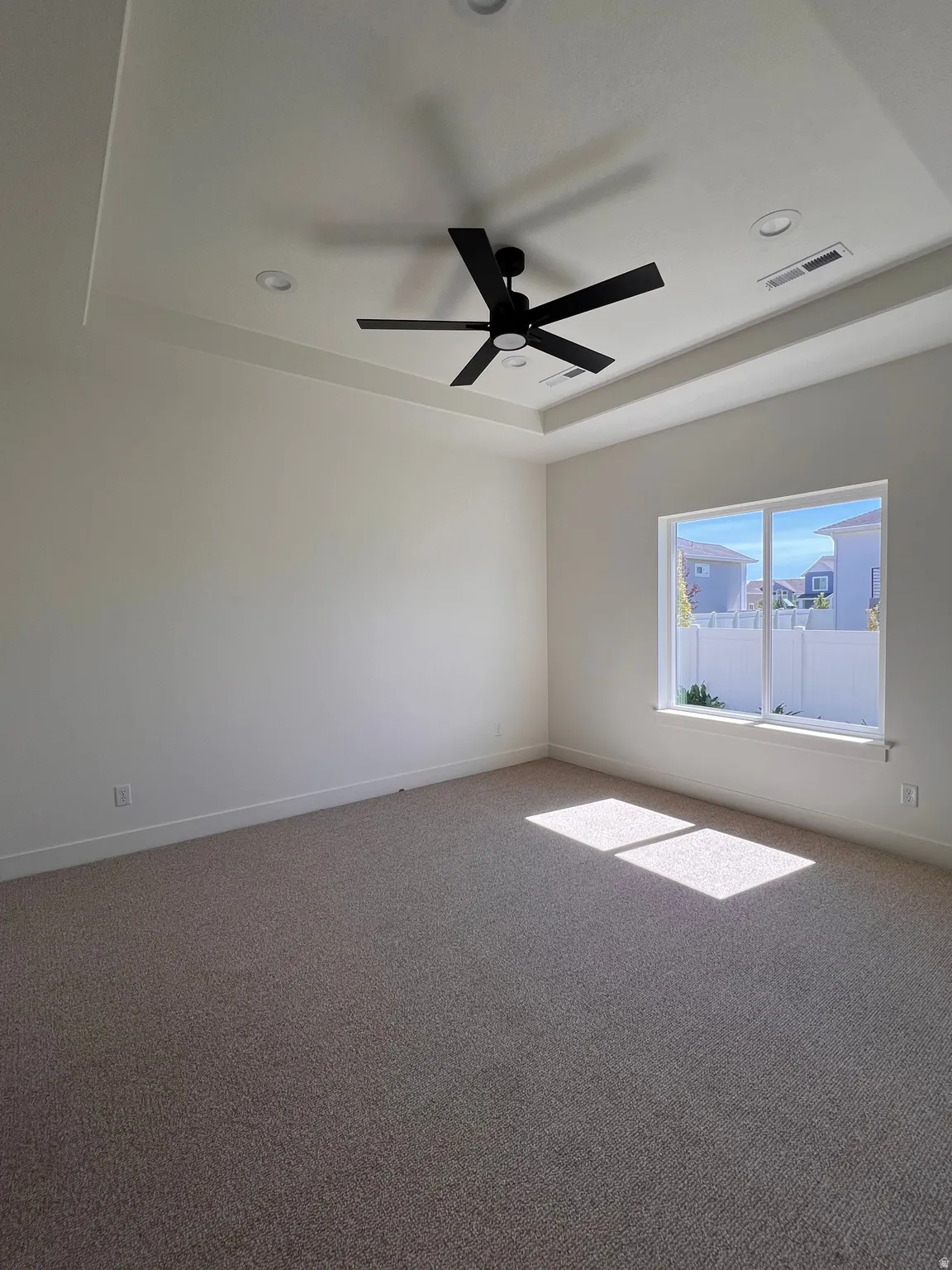 Recessed lighting, tray ceiling, black ceiling fan, and carpet flooring