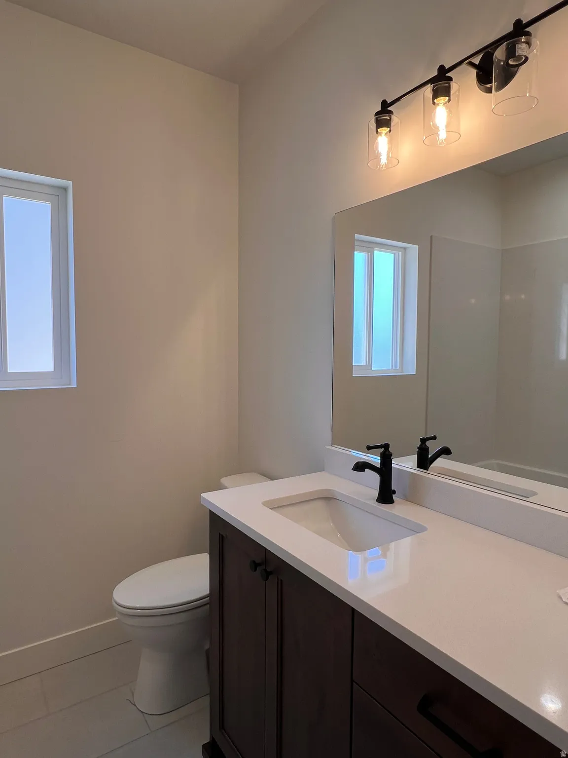 Dark wood-finish vanity with white countertop, integrated sink, and matte black faucet
