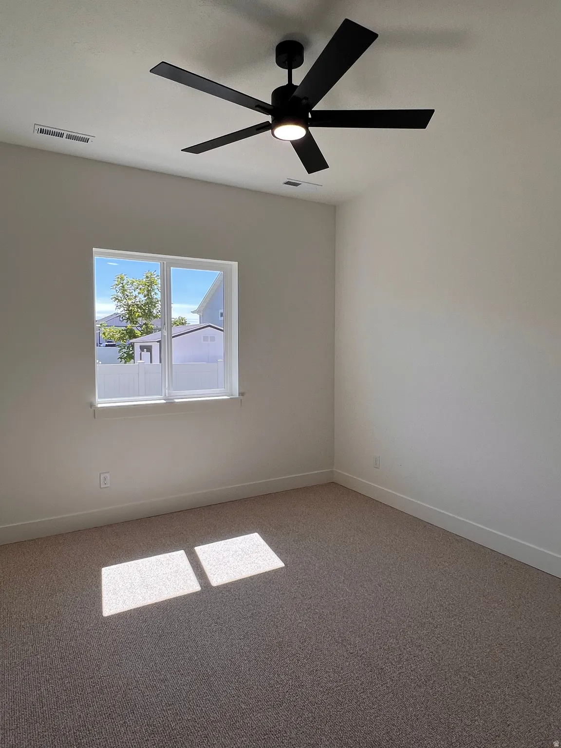 Neutral-toned carpeting, white walls, and a window with white trim