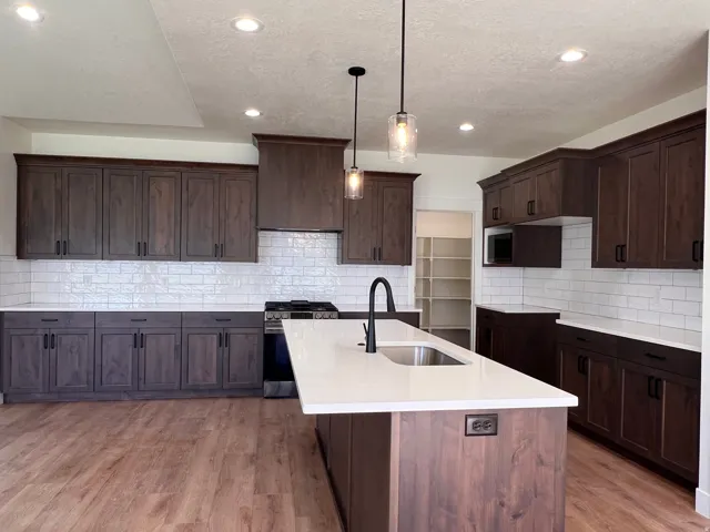 Kitchen featuring dark wood-finish cabinetry, white countertops, a subway tile backsplash, and wood-finish flooring