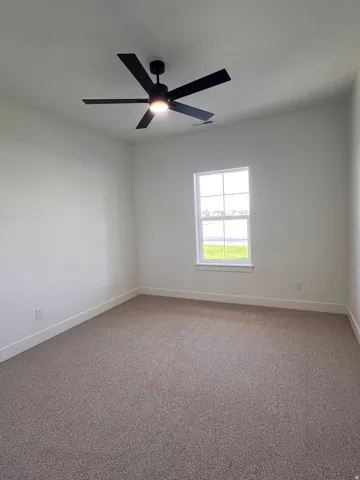 Neutral wall finishes, a window with white trim, a dark ceiling fan with integrated lighting, and carpeted flooring