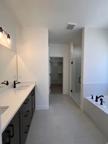 Dual vanity with dark wood-finish cabinetry, white countertops, and matte black fixtures