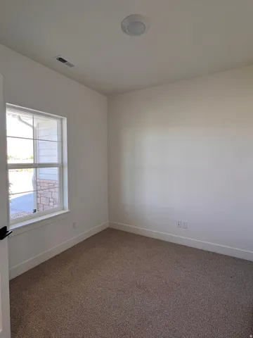Recessed ceiling lighting, textured carpet flooring, white painted walls, and a white window frame