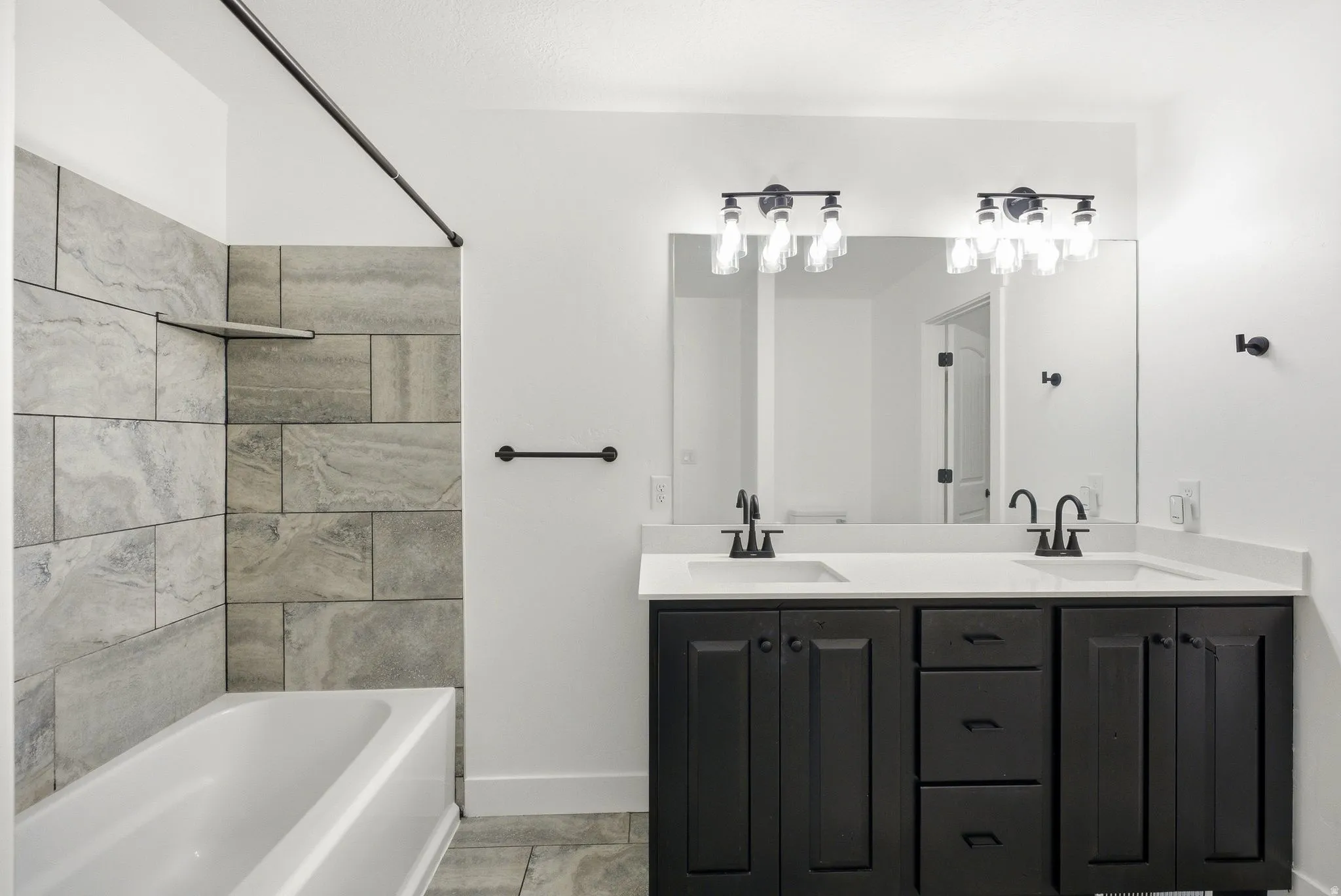 Double vanity with dark wood-finish cabinetry, white countertop, and matte black fixtures