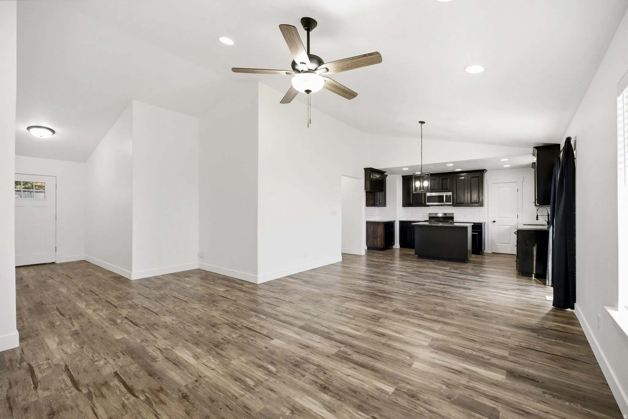 Open-concept living space featuring wood-finish flooring, a ceiling fan, and recessed lighting