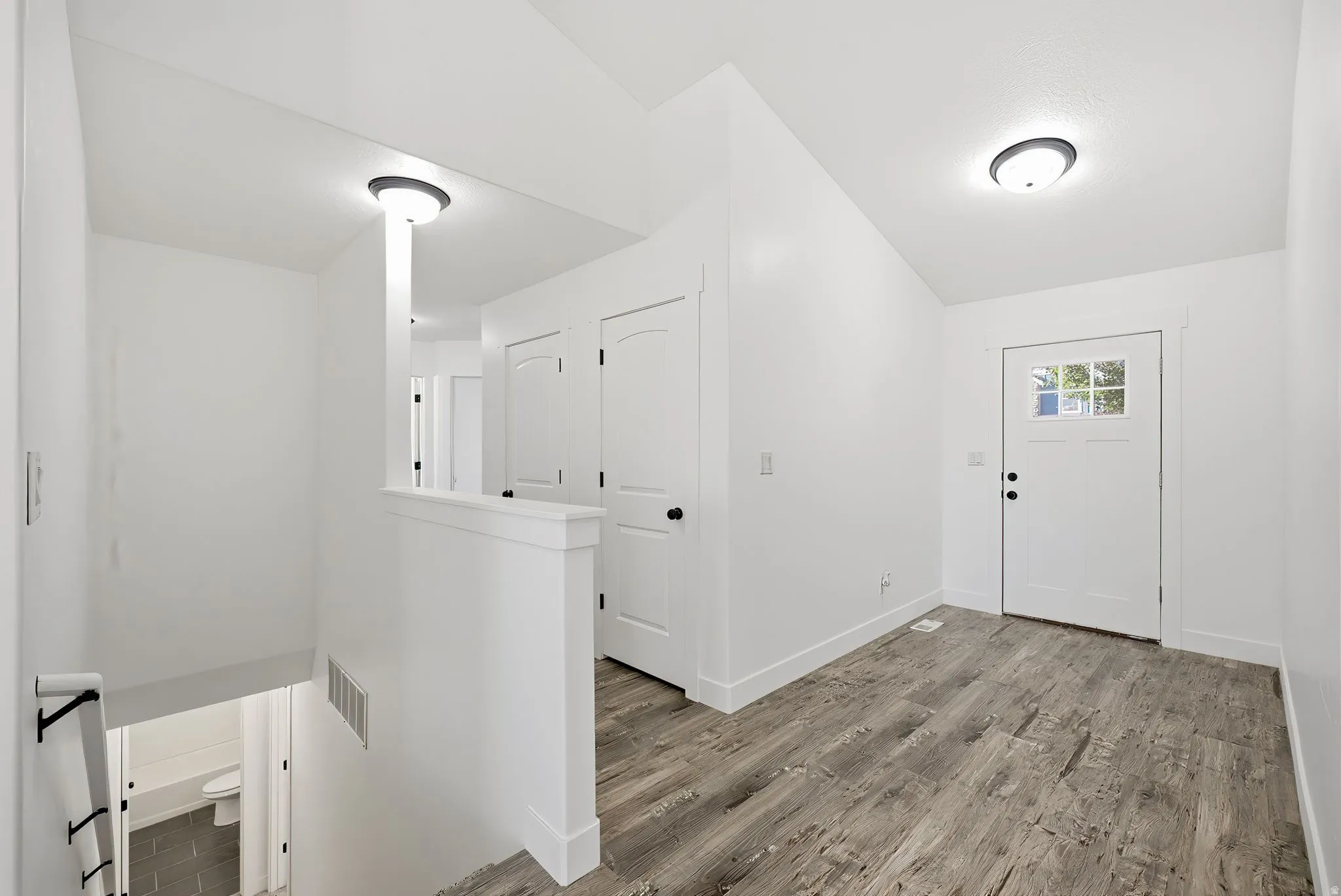 Entryway featuring wood-finish flooring, a white paneled door with glass inserts, and modern flush-mount lighting