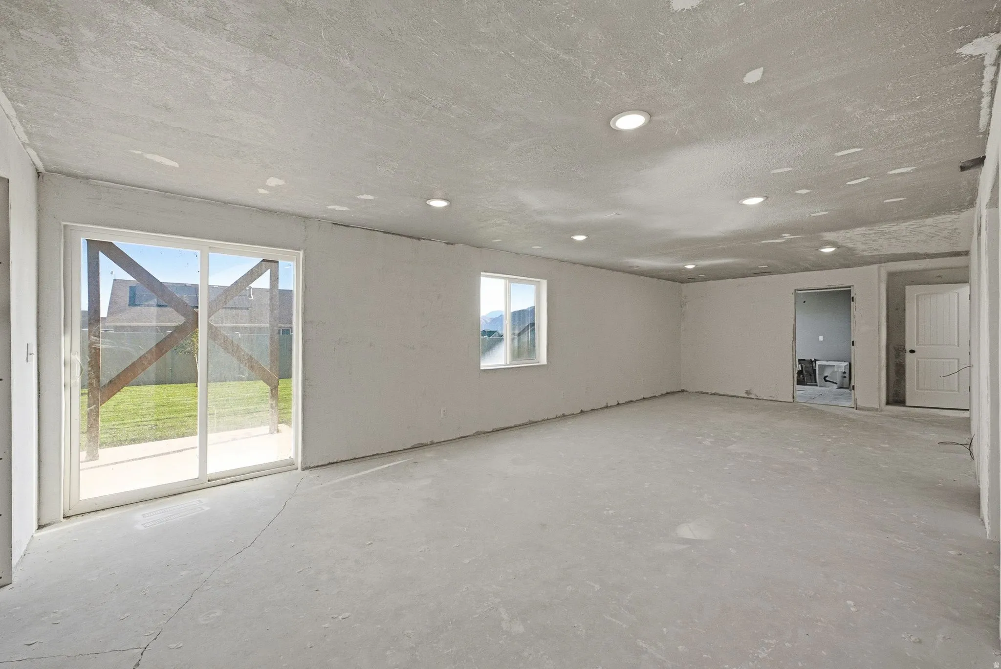 Spacious room featuring multiple recessed lights, a sliding glass door, and an additional window