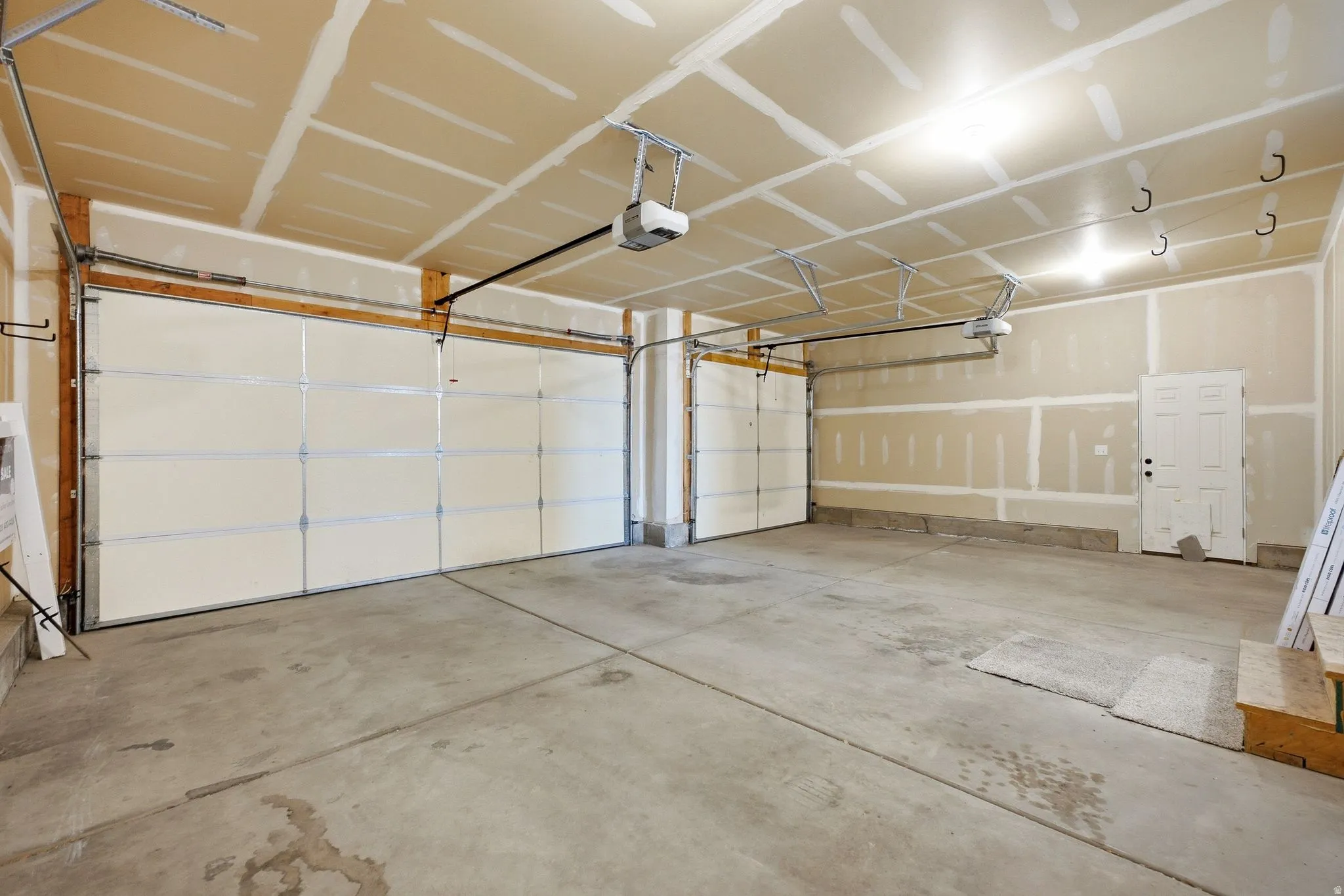 Spacious garage featuring concrete flooring, two overhead garage doors, and integrated garage door openers
