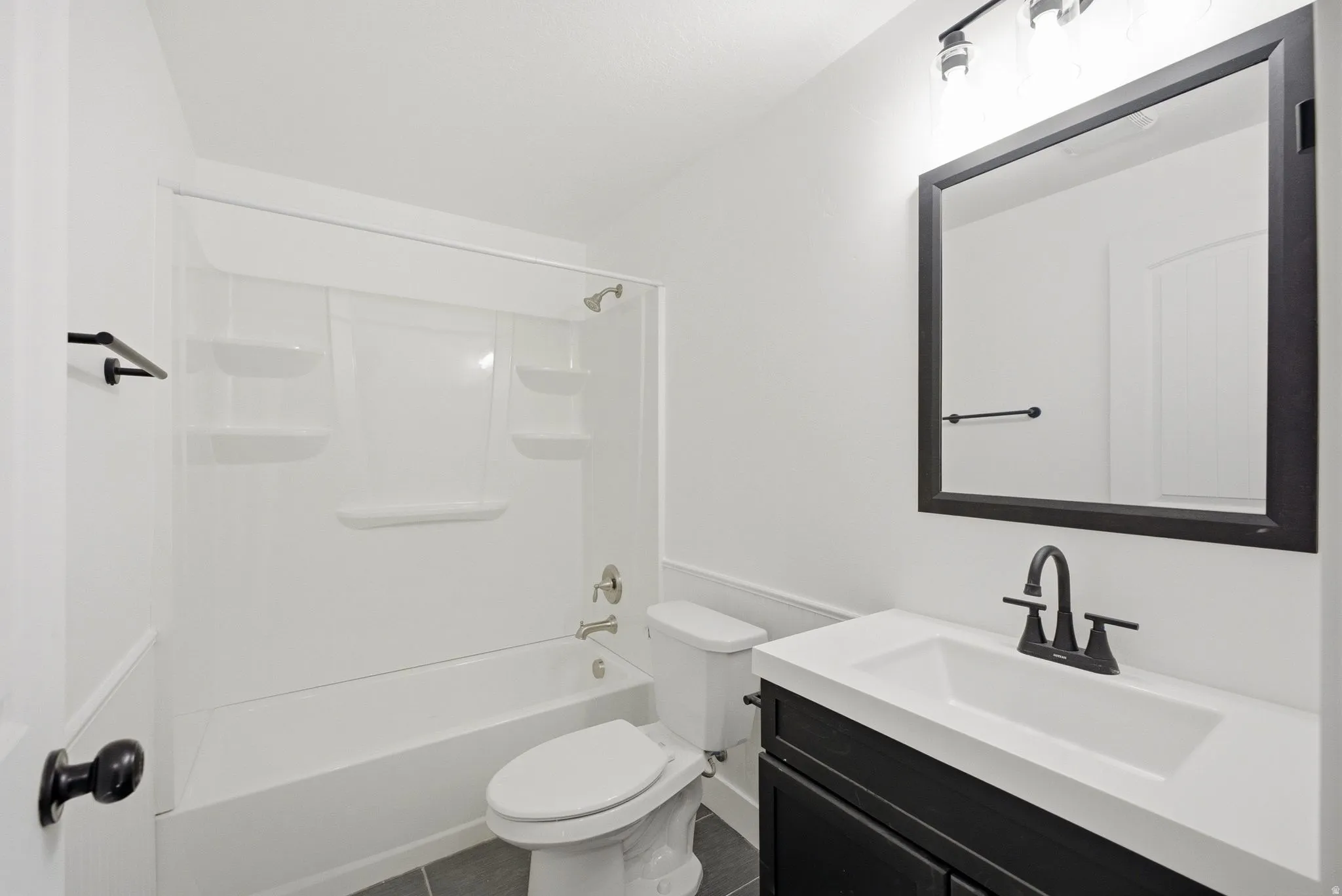 White vanity with integrated sink, black cabinet, black framed mirror, and black faucet