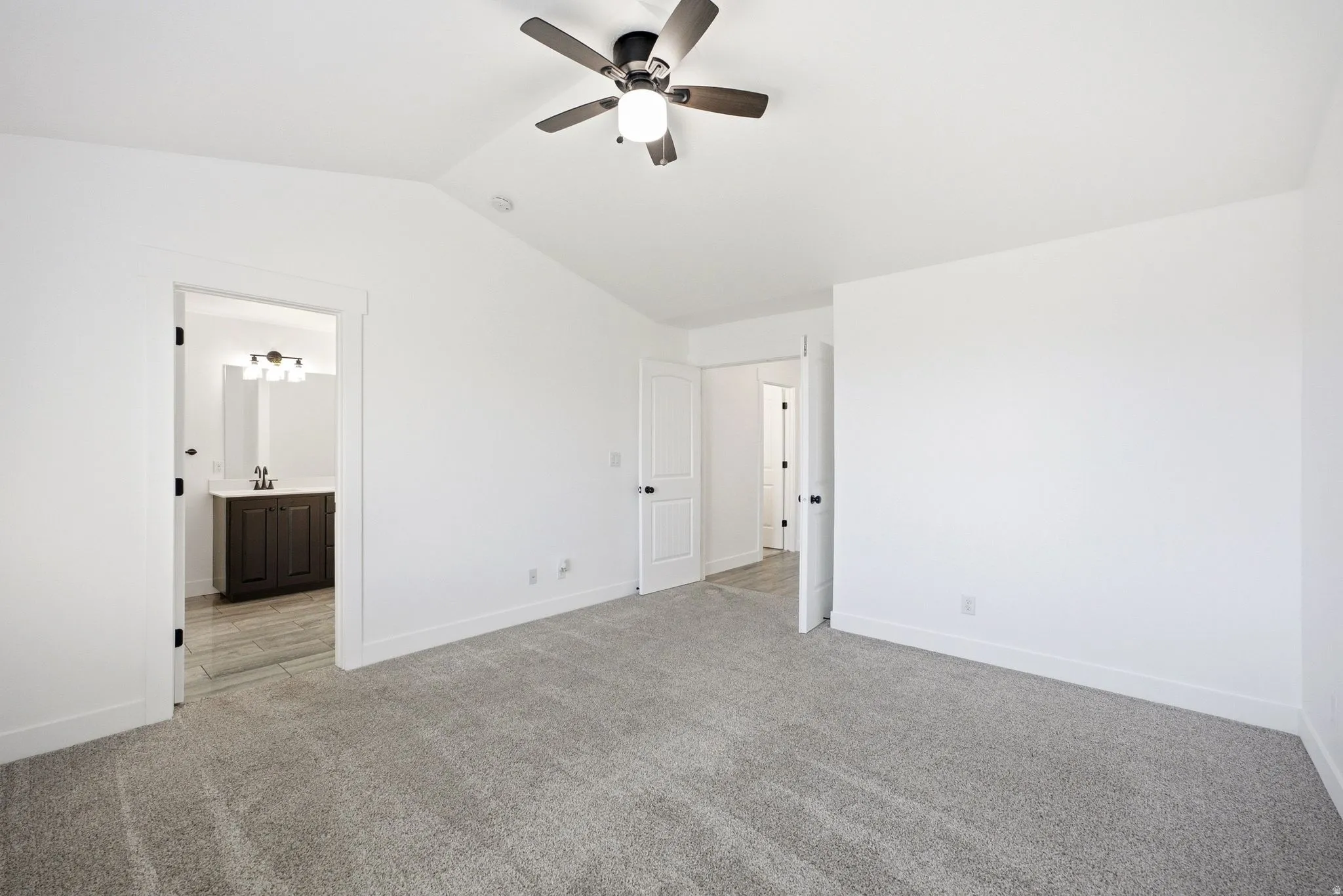 Gray carpeting and white walls with a ceiling fan light fixture