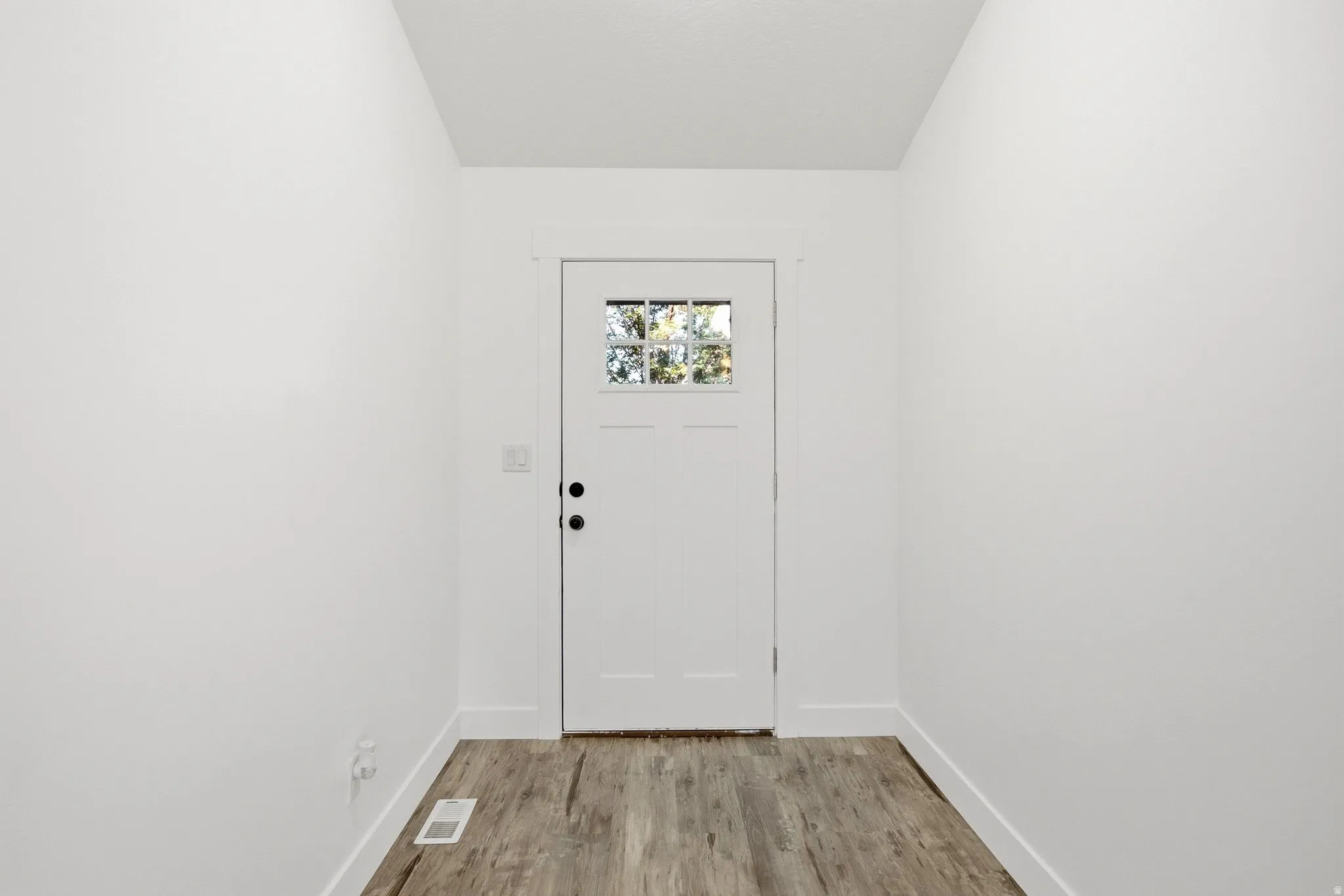 Entryway featuring a white paneled door with glass inserts, wood-finish flooring, and white trim