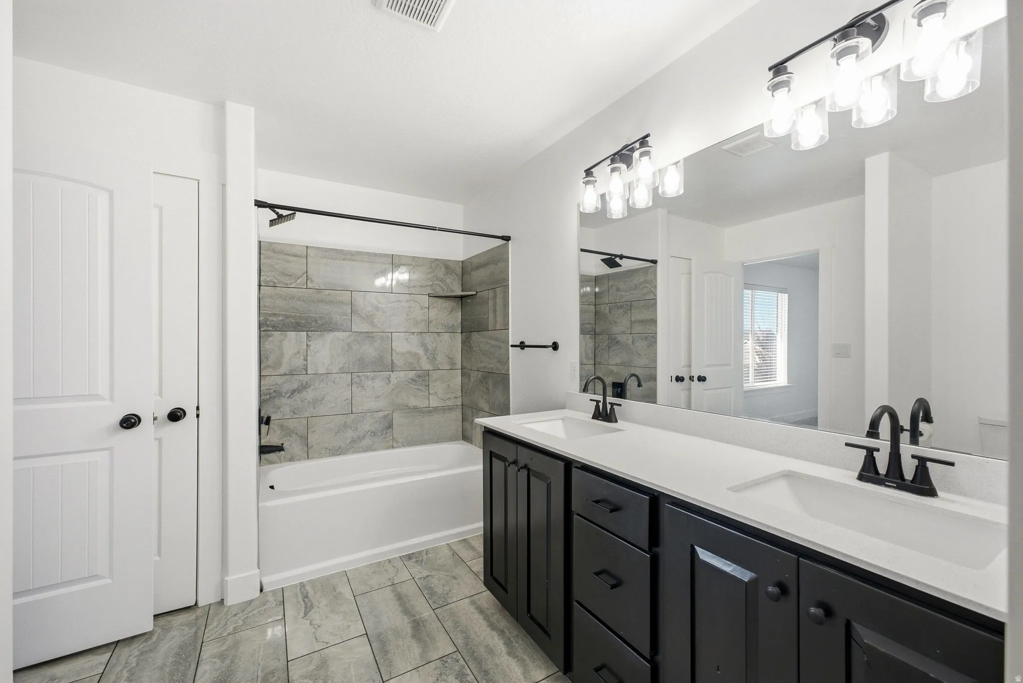 Dual vanity with dark cabinetry, white countertops, and matte black fixtures