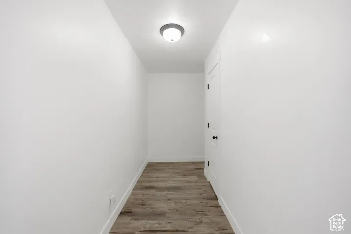 Hallway featuring wood-finish flooring, white walls, and a flush-mount ceiling light