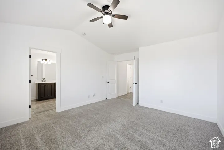 Gray carpeting and white walls with a ceiling fan light fixture