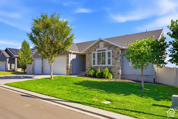 Stone and stucco exterior with multiple windows, an attached two-car garage, and a manicured lawn