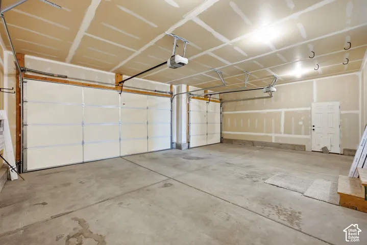 Spacious garage featuring concrete flooring, two overhead garage doors, and integrated garage door openers