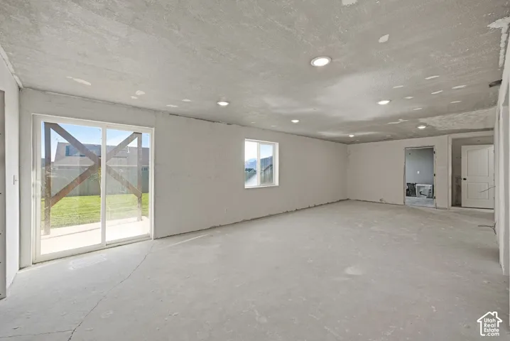 Spacious room featuring multiple recessed lights, a sliding glass door, and an additional window
